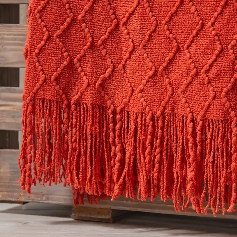 Manta de punto grueso con flecos estilo boho sobre cama